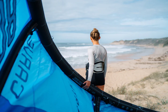 Kitesurfer holding their kite looking out at the sea