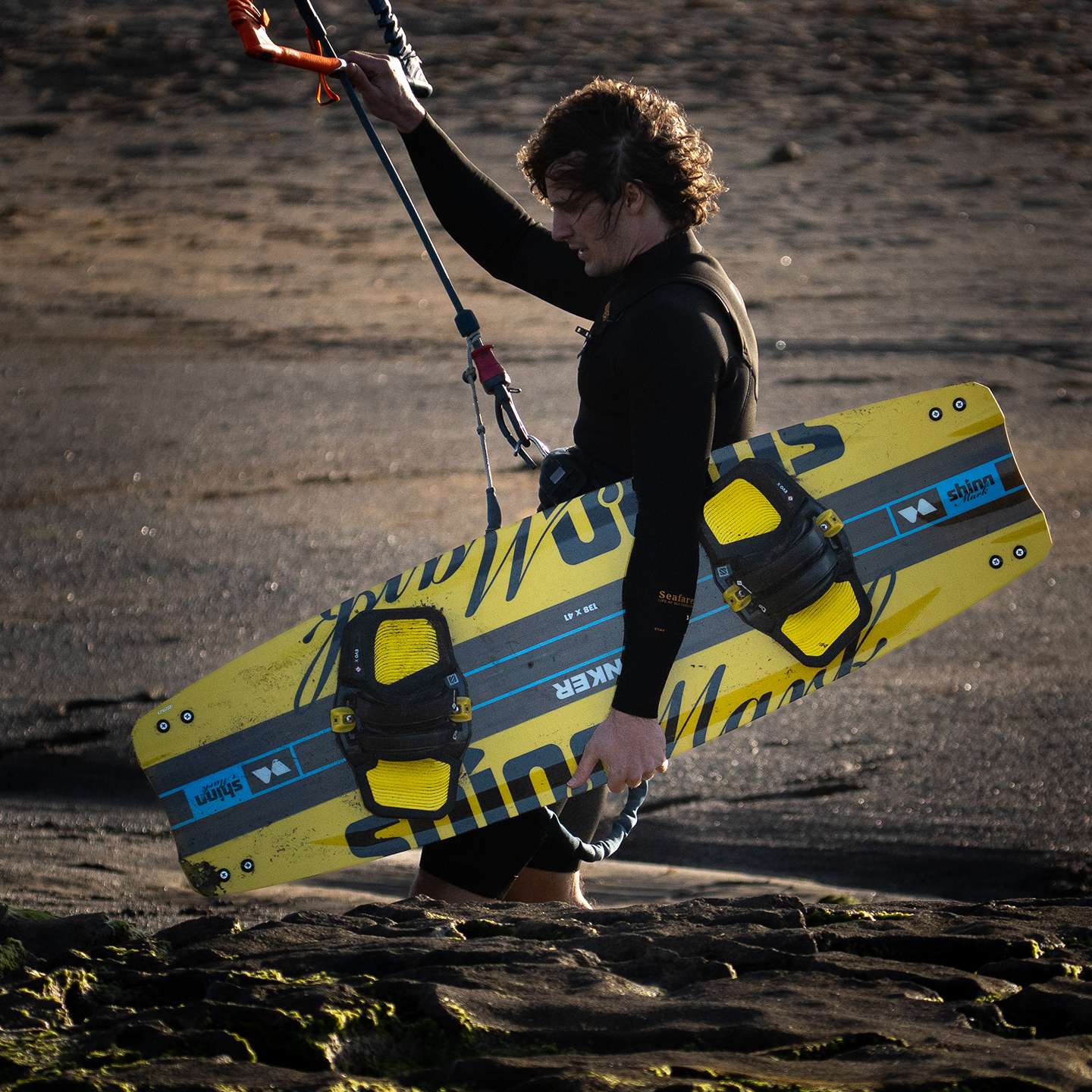 Shinn Monker Kiteboard 2025 base view showing the underside graphic, channels and rocker profile